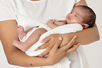 Glückliche Mutter mit Baby auf dem Arm